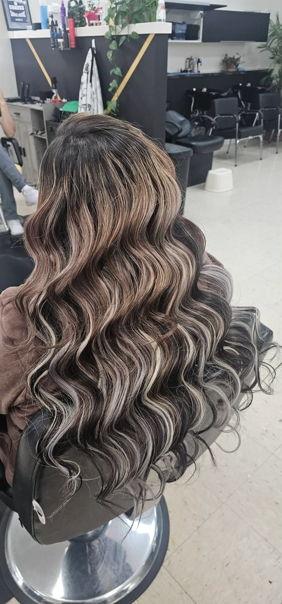Cabello largo ondulado con base oscura y mechas balayage rubio plateado