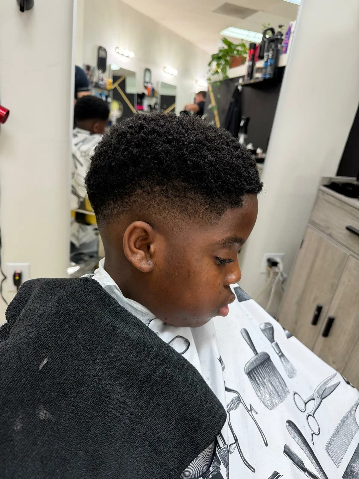 Parte superior rizada de un niño con un taper fade limpio
